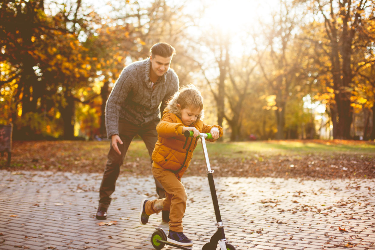 Boy learning how to ride scooter